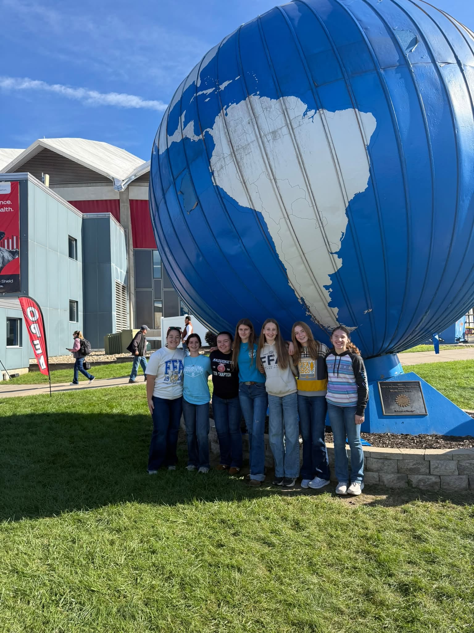Members standing in front of a large blue globe at World Dairy Expo.