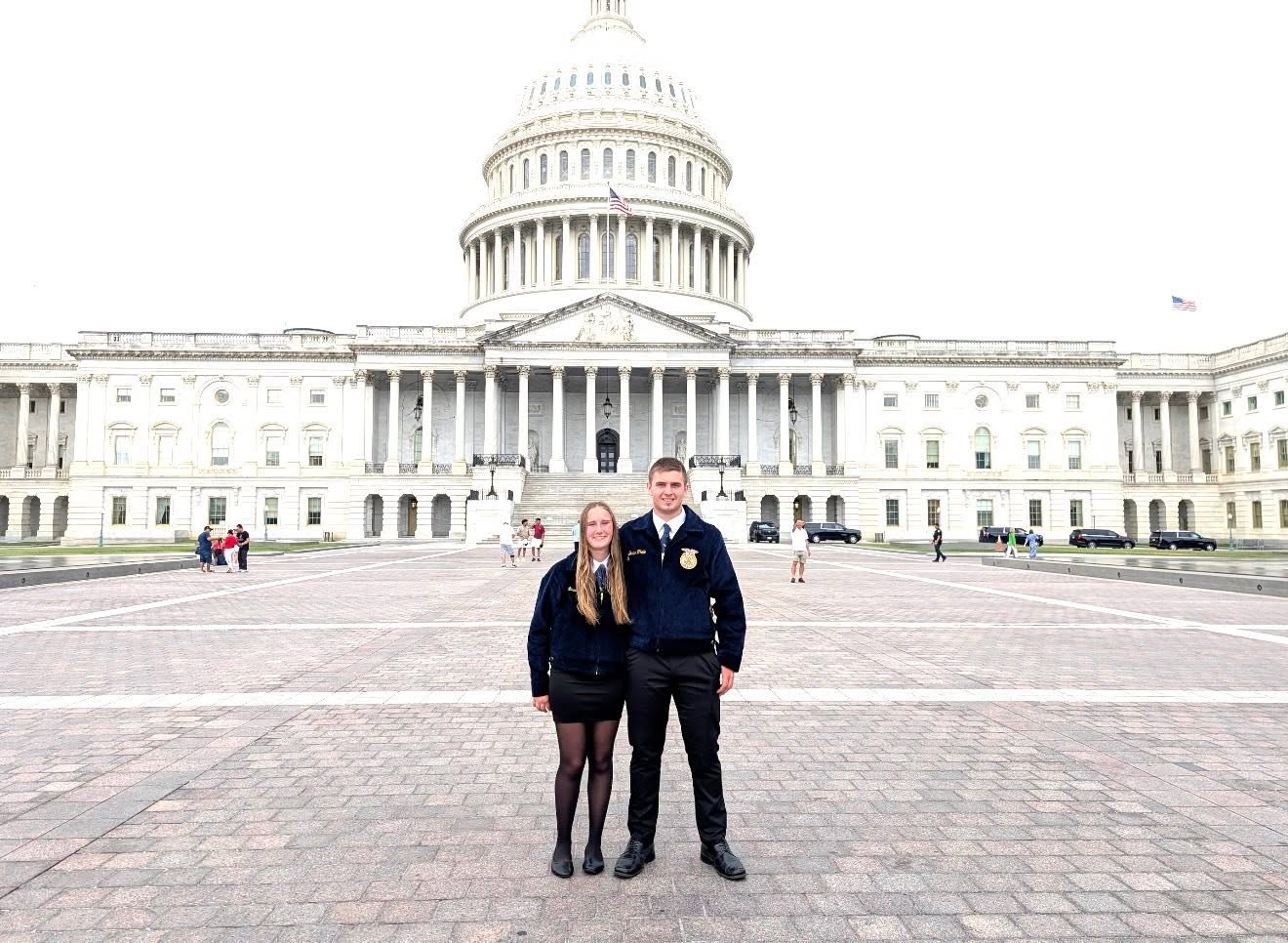 Two members stand in the plaza in front of the U.S. Capitol.