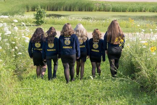 The six officers walk away through tall grass, with FFA lettering on the backs of their jackets.