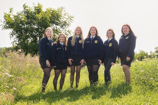 The six officers in blue FFA jackets stand together in a field.