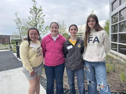 Four floriculture team members holding ribbons and flower arrangements.