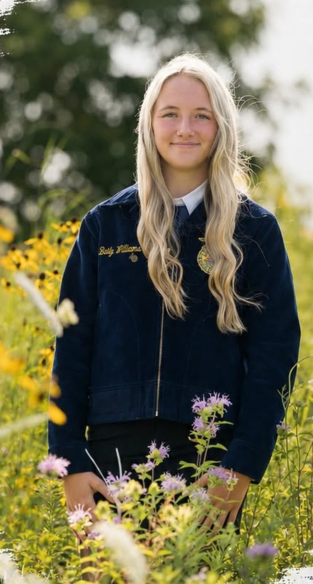 Baily Williams in her FFA jacket, standing in a field of wildflowers.
